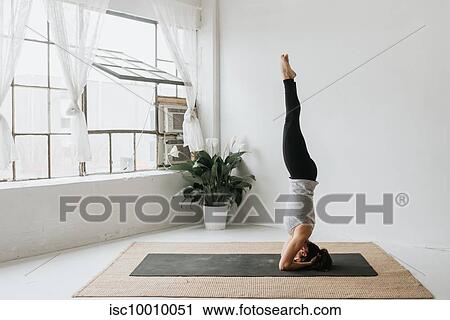 Stock Image - Woman practising yoga in studio. Fotosearch