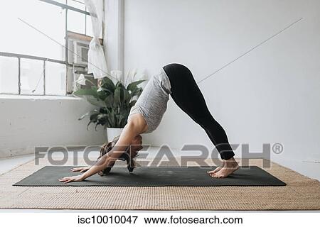 Stock Photo - Woman practising yoga in studio. Fotosearch