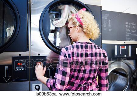 Woman pressing washing machine buttons at laundrette View Large Photo Image Stock Image - Woman pressing washing machine buttons at laundrette. Fotosearch