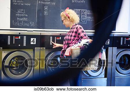 Woman pressing washing machine buttons at laundrette View Large Photo Image Stock Image - Woman pressing washing machine buttons at laundrette. Fotosearch