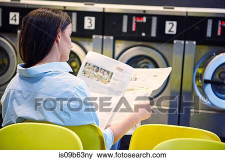 Woman reading newspaper in laundrette View Large Photo Image Stock Photo - Woman reading newspaper in laundrette. Fotosearch