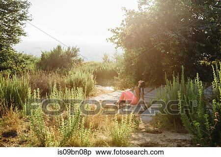 Stock Photography - Woman relaxing among shrubs on hilltop. Fotosearch