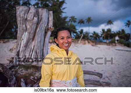 Stock Image - Woman relaxing by old tree trunk, Kailua Beach, Oahu, Hawaii. Fotosearch