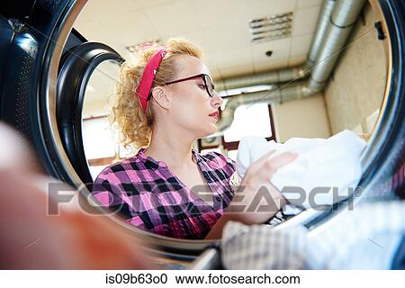 Woman removing laundry from tumble dryer in laundrette View Large Photo Image Stock Image - Woman removing laundry from tumble dryer in laundrette. Fotosearch