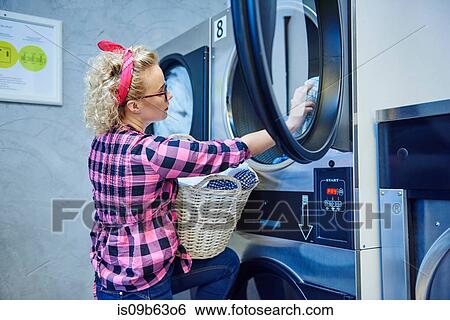 Woman removing laundry from tumble dryer in laundrette View Large Photo Image Stock Photograph - Woman removing laundry from tumble dryer in laundrette. Fotosearch