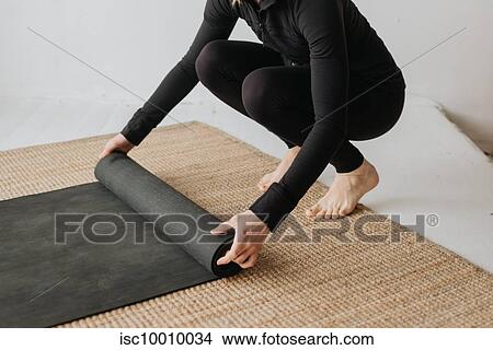 Woman rolling yoga mat in studio View Large Photo Image Picture - Woman rolling yoga mat in studio. Fotosearch