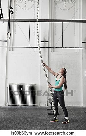 Woman rope climbing in cross training gym View Large Photo Image Picture - Woman rope climbing in cross training gym. Fotosearch