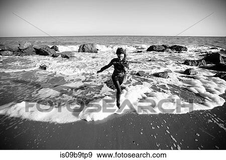 Stock Photo - Woman running from ocean wave on beach, Odessa Oblast, Ukraine. Fotosearch
