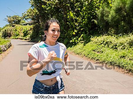 Stock Image - Woman running on road, Waipipi Trail, Maui, Hawaii. Fotosearch