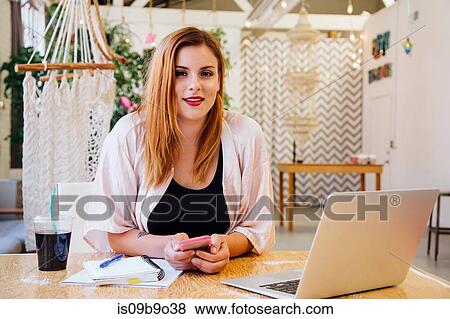 Woman sitting at desk in creative studio looking at camera smiling View Large Photo Image Stock Photo - Woman sitting at desk in creative studio looking at camera smiling. Fotosearch