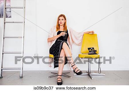 Stock Photo - Woman sitting in swivel chair with drink looking away. Fotosearch