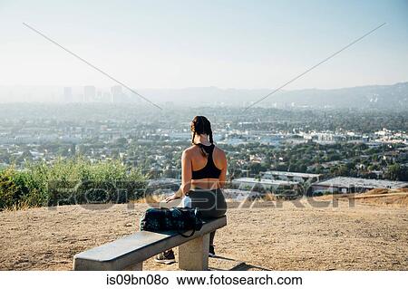 Woman sitting on bench on hilltop, Los Angeles, US View Large Photo Image Picture - Woman sitting on bench on hilltop, Los Angeles, US. Fotosearch