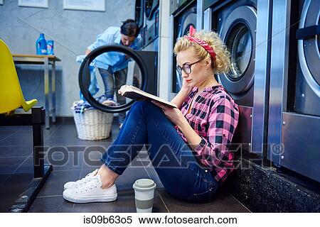 Woman sitting on laundrette floor reading book View Large Photo Image Stock Photography - Woman sitting on laundrette floor reading book. Fotosearch