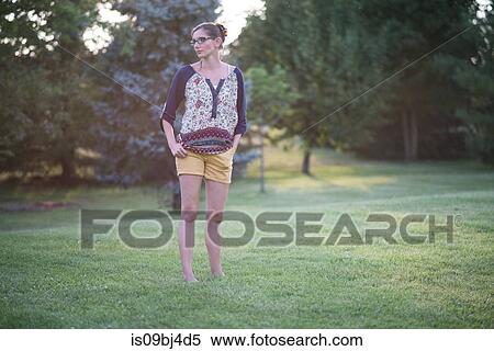 Stock Photography - Woman standing in park at sunset. Fotosearch