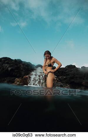 Woman standing in sea by rocks, Princeville, Hawaii, US View Large Photo Image Stock Image - Woman standing in sea by rocks, Princeville, Hawaii, US. Fotosearch