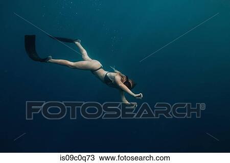 Stock Image - Woman swimming underwater. Fotosearch