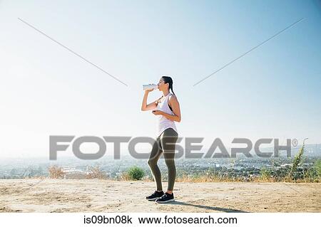 Woman taking break, drinking on hilltop View Large Photo Image Stock Image - Woman taking break, drinking on hilltop. Fotosearch