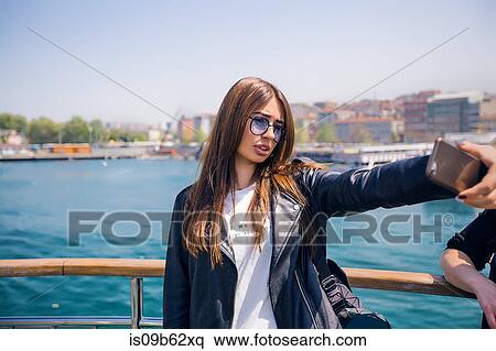 Woman taking selfie, sea in background View Large Photo Image Stock Photography - Woman taking selfie, sea in background. Fotosearch