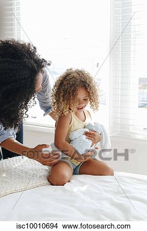 Woman talking to little girl cradling soft toy on bed View Large Photo Image Picture - Woman talking to little girl cradling soft toy on bed. Fotosearch