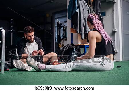 Woman talking to young man tying shoelace in gym View Large Photo Image Stock Photo - Woman talking to young man tying shoelace in gym. Fotosearch