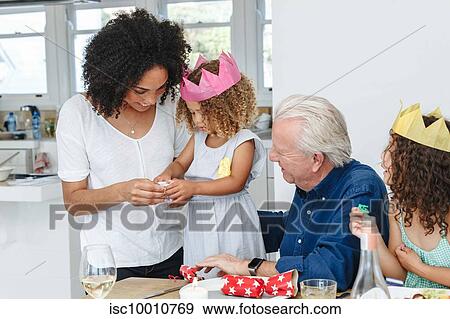 Stock Photo - Woman teaching daughter fold paper flower at dining table. Fotosearch
