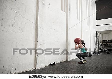 Woman throwing fitness ball against wall in cross training gym View Large Photo Image Stock Image - Woman throwing fitness ball against wall in cross training gym. Fotosearch