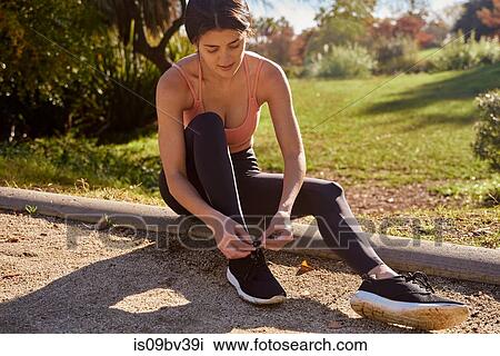 Woman tying shoelace in city park View Large Photo Image Stock Image - Woman tying shoelace in city park. Fotosearch