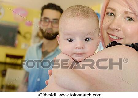 Woman with baby boy, husband in background View Large Photo Image Stock Photograph - Woman with baby boy, husband in background. Fotosearch
