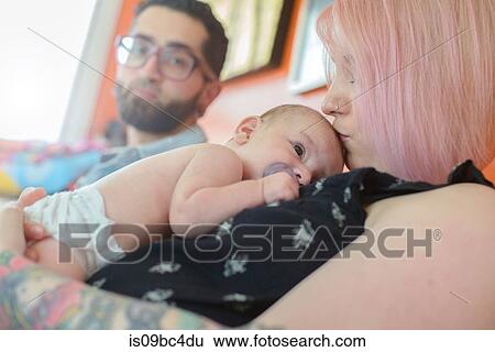 Woman with baby boy on chest, husband in background View Large Photo Image Stock Photograph - Woman with baby boy on chest, husband in background. Fotosearch