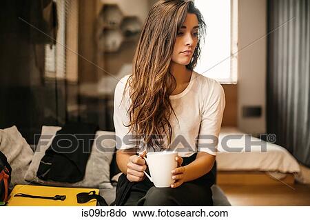 Picture - Woman with cup contemplating in bedroom. Fotosearch