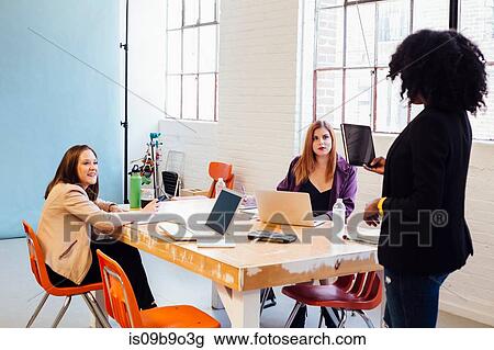 Woman with digital tablet speaking to colleagues working at desk View Large Photo Image Stock Image - Woman with digital tablet speaking to colleagues working at desk. Fotosearch