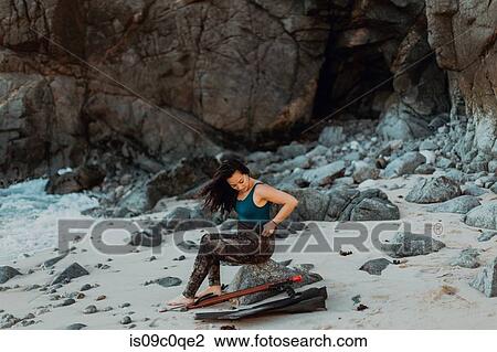 Stock Image - Woman with flippers and speargun on beach, Big Sur, California, United States. Fotosearch