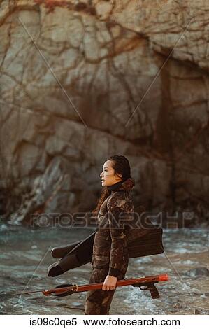 Stock Photography - Woman with flippers and speargun on beach, Big Sur, California, United States. Fotosearch
