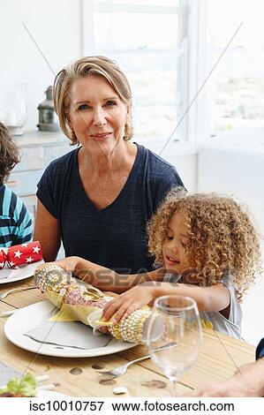 Woman with granddaughter playing with Christmas cracker at dining table View Large Photo Image Stock Photo - Woman with granddaughter playing with Christmas cracker at dining table. Fotosearch