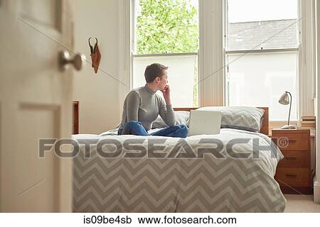 Woman with laptop, daydreaming on bed View Large Photo Image Stock Image - Woman with laptop, daydreaming on bed. Fotosearch