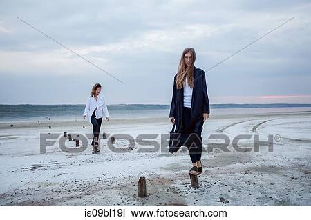 Stock Image - Women balancing on wooden stumps on beach, Odessa, Ukraine. Fotosearch