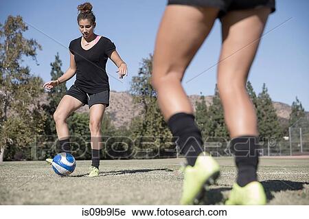 Stock Image - Women on football pitch playing football. Fotosearch