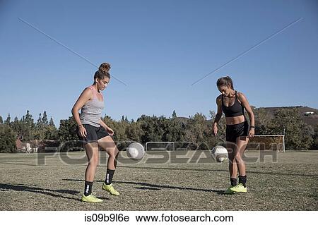 Stock Image - Women on football pitch playing football. Fotosearch