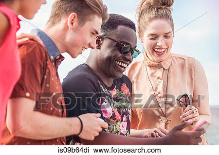 Young adult friends looking at smartphone View Large Photo Image Stock Image - Young adult friends looking at smartphone. Fotosearch