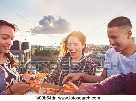 Young adult friends sharing pizza at roof party in London, UK View Large Photo Image Stock Photography - Young adult friends sharing pizza at roof party in London, UK. Fotosearch
