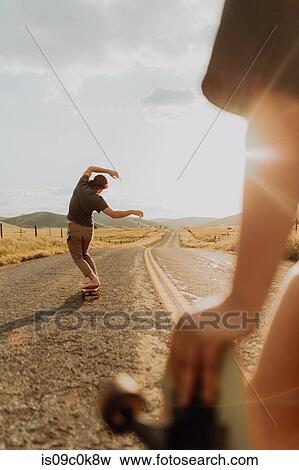 Young barefoot male skateboarder skateboarding on rural road, girlfriend watching, Exeter, California, USA View Large Photo Image Stock Photo - Young barefoot male skateboarder skateboarding on rural road, girlfriend watching, Exeter, California, USA. Fotosearch
