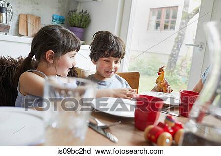 Young boy and girl sitting at dinner table, smiling View Large Photo Image Stock Image - Young boy and girl sitting at dinner table, smiling. Fotosearch