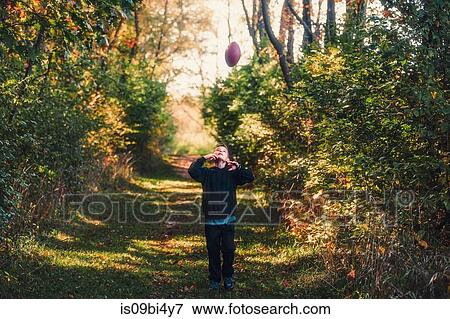 Young boy in rural setting, throwing american football in air View Large Photo Image Stock Photo - Young boy in rural setting, throwing american football in air. Fotosearch