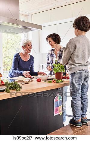 Young boy, mother and grandmother making pizza together in kitchen View Large Photo Image Stock Photo - Young boy, mother and grandmother making pizza together in kitchen. Fotosearch