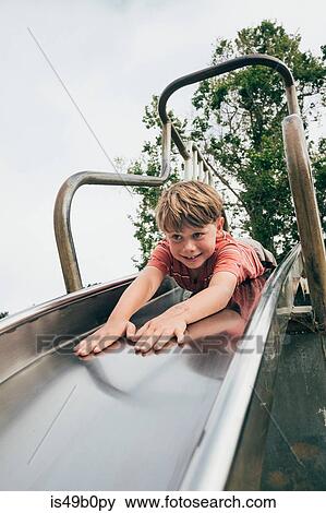 Stock Photo - Young boy sliding down slide on stomach, Santa Barbara, California, USA. Fotosearch