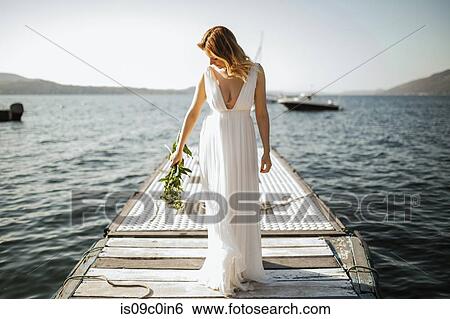 Young bride in wedding dress standing on lake pier, Stresa, Piemonte, Italy View Large Photo Image Stock Photograph - Young bride in wedding dress standing on lake pier, Stresa, Piemonte, Italy. Fotosearch