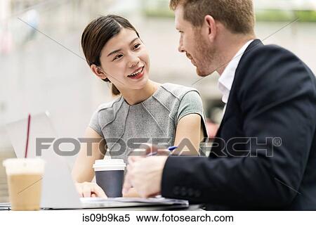 Stock Photography - Young businessman and woman having discussion at sidewalk cafe. Fotosearch