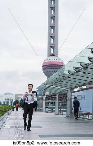 Young businessman looking strolling in city, Shanghai, China View Large Photo Image Stock Image - Young businessman looking strolling in city, Shanghai, China. Fotosearch