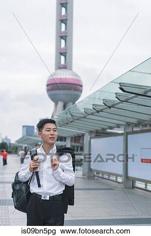 Young businessman looking strolling in city, Shanghai, China View Large Photo Image Stock Image - Young businessman looking strolling in city, Shanghai, China. Fotosearch