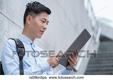 Stock Image - Young businessman using digital tablet on city stairway, Shanghai, China. Fotosearch